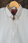 Light gray shirt with a visible brand label on a wooden hanger against a dark background