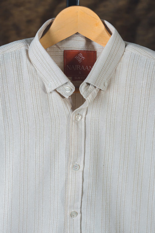 Light gray shirt with a visible brand label on a wooden hanger against a dark background