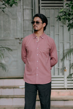 A man wearing a dusty rose pink long-sleeve button-down shirt and black trousers by NAJRAAN